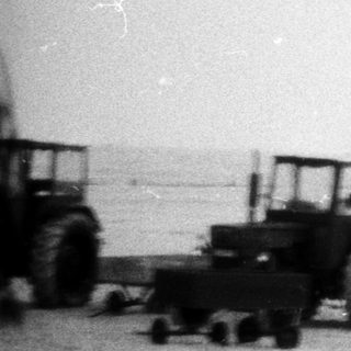 Beached boat and construction vehicles on shore.