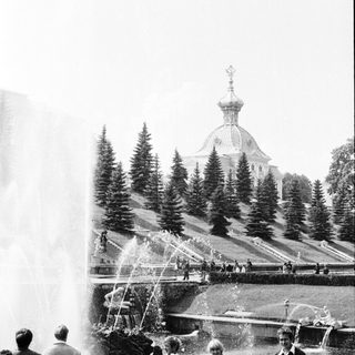 Historic park with fountain, church, and visitors.