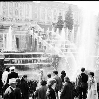 People enjoying large fountain show in grand park setting.