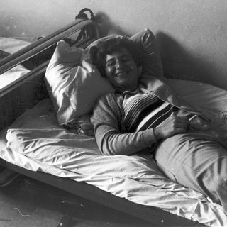 Person lying in hospital bed smiling.
