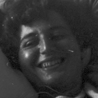 Person lying in hospital bed smiling.