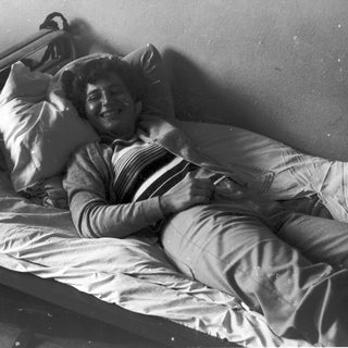 Person lying in hospital bed smiling.