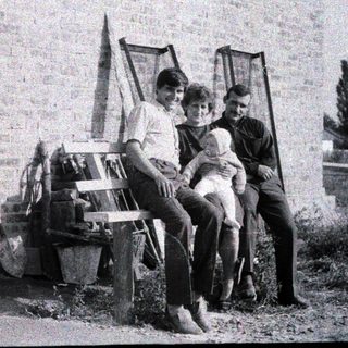 Three people posing together outdoors on a bench.