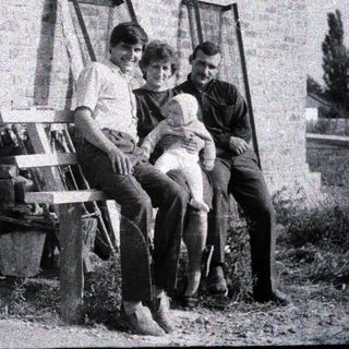 Three people posing together outdoors on a bench.