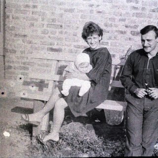 Family portrait with mother, father, and baby outdoors.