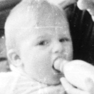 A woman feeding a baby on a couch.