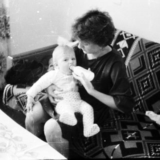 A woman feeding a baby on a couch.