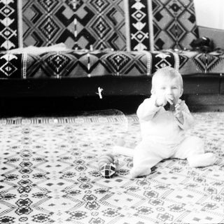 Baby playing with toy on patterned floor.