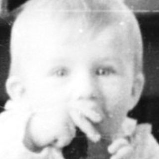 Baby playing with toy on patterned floor.