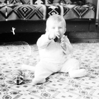 Baby playing with toy on patterned floor.