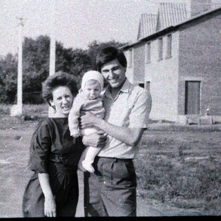 Family portrait with mother, father, and baby outdoors.