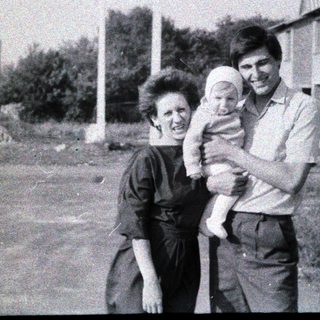Family portrait with mother, father, and baby outdoors.