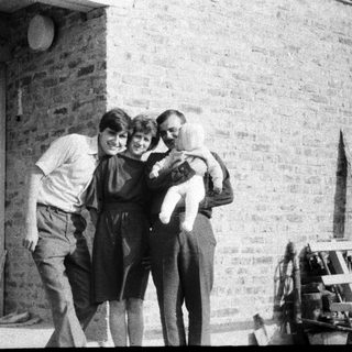 Family group hug outside brick building.