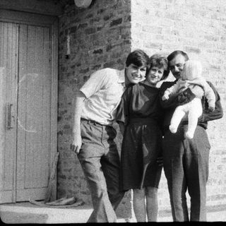 Family group hug outside brick building.