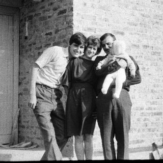 Family group hug outside brick building.