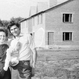 Two adults holding a baby outdoors.