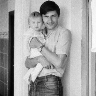 A man holding a smiling baby indoors.