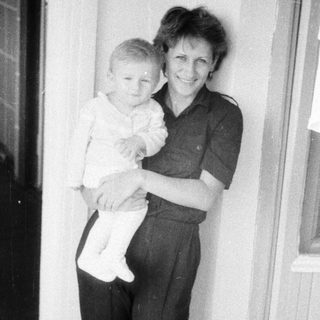 A woman holding a young child indoors.