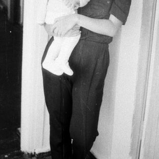 A woman holding a young child indoors.