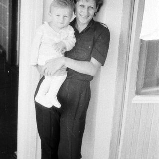 A woman holding a young child indoors.