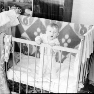 Baby sitting in a crib.