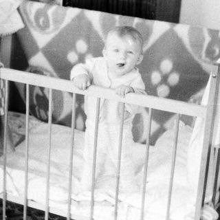 Baby sitting in a crib.