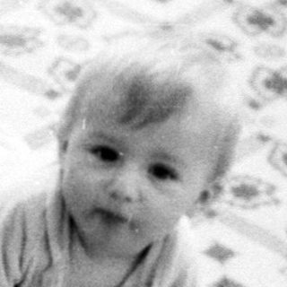 Baby crawling on patterned floor mat.