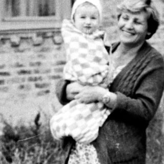 Family portrait with mother holding baby outdoors.