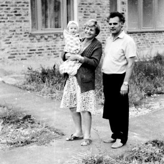 Family portrait with mother holding baby outdoors.