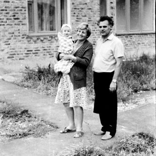 Family portrait with mother holding baby outdoors.