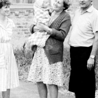 Four people standing outside brick building.