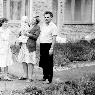 Four people standing outside brick building.
