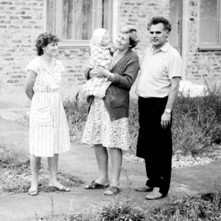 Four people standing outside brick building.