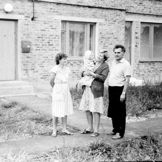 Four people standing outside brick building.