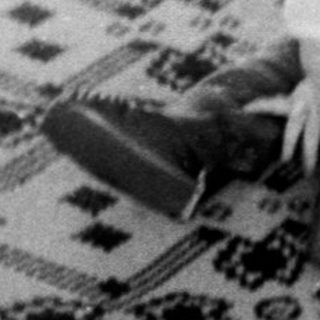 Baby sitting on patterned rug indoors.