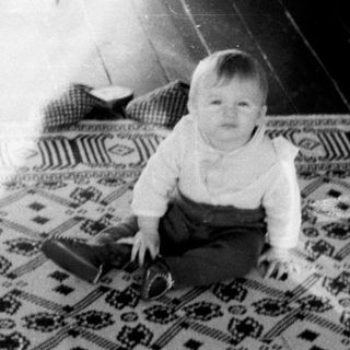 Baby sitting on patterned rug indoors.