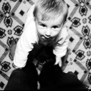 Child making peace sign indoors.
