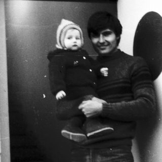A man holding a baby near an open doorway.