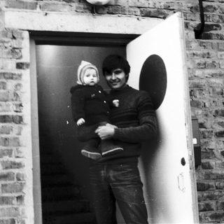 A man holding a baby near an open doorway.