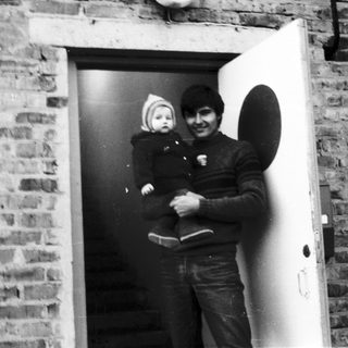 A man holding a baby near an open doorway.