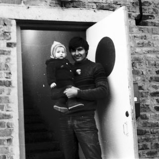 A man holding a baby near an open doorway.