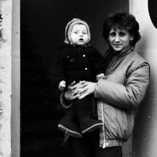A woman holding a young child near a doorway.