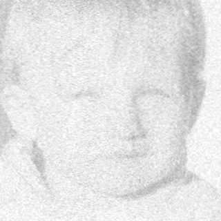 Baby sitting on patterned rug indoors.