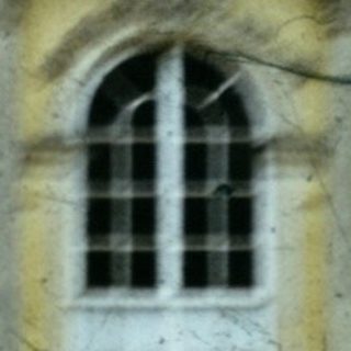 Neoclassical building facade with arched windows, blurred figure walking.