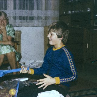 Two people playing indoor badminton with yellow balls.