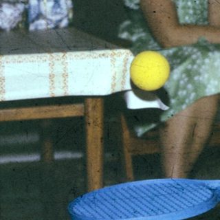 Two people playing indoor badminton with yellow balls.