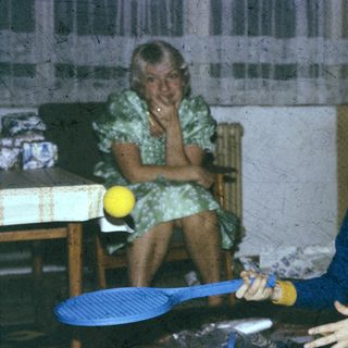 Two people playing indoor badminton with yellow balls.