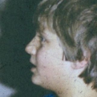 A woman knitting while a child prays or claps.
