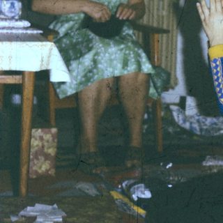 A woman knitting while a child prays or claps.