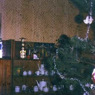 Cozy kitchen shelf with festive tea set and Christmas tree.